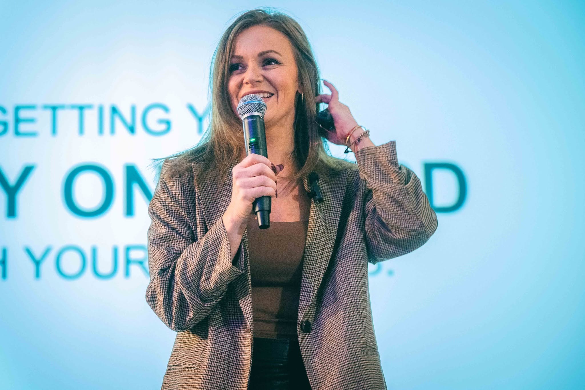 Cynthia speaking on stage with a microphone during a corporate keynote