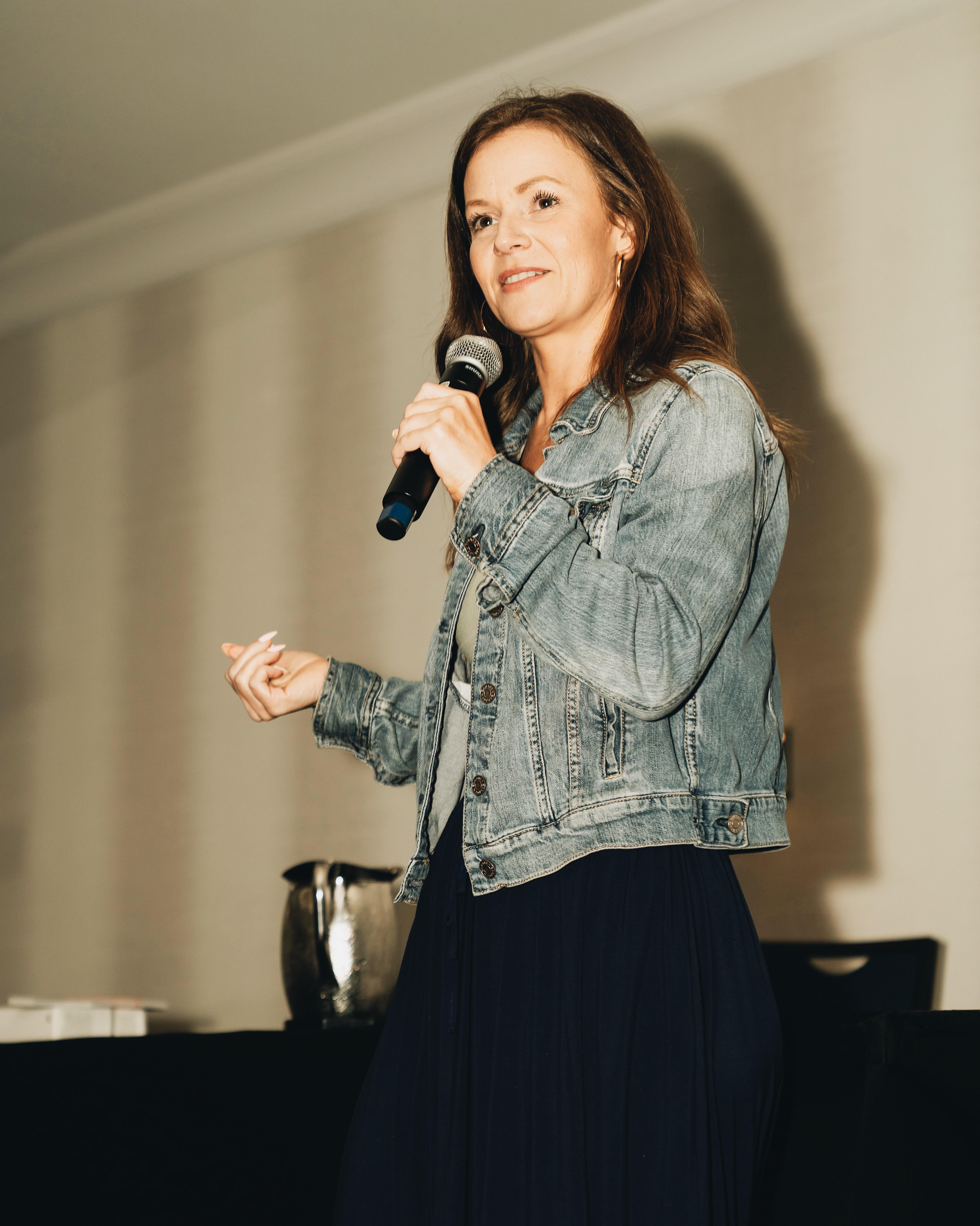 Cynthia smiling and speaking with a microphone in hand